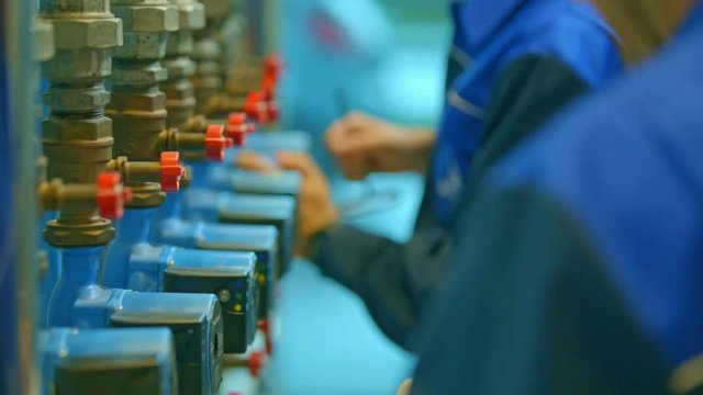 Two workers in a factory are trying to fix a few items. They are making sure all the items are okay and ready to be shipped to customers. 