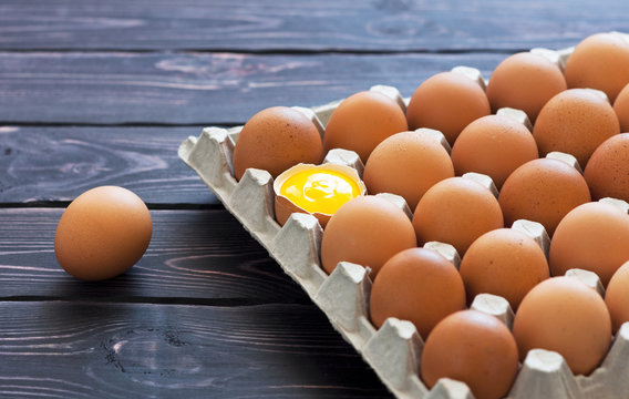 Top view of chicken eggs in a cardboard box on a dark wooden table with copy space.