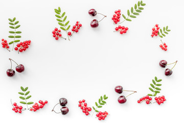 Berry ornament. Red currant, cherry and leaves on white background top view copyspace