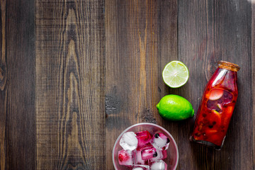 Bottle of fresh lemonade, fruits and ice cubes on wooden background top view copyspace