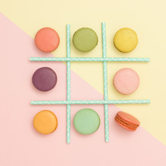 Tick-tack-toe made of macaroons and straws on pastel background. Flat lay. Healthy food concept.