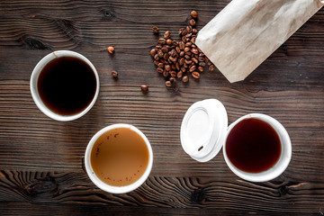 Coffee take away. Coffee cups with covers and coffee beans on wooden table backound top view