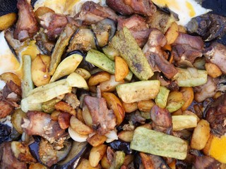 Fried vegetables and meat in a large frying pan. Background