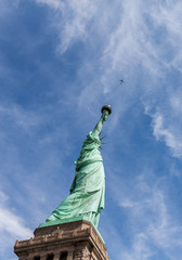 statue de la Libert&eacute; pointant un avion