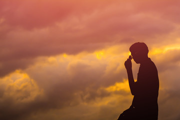 Obraz premium Silhouette of young man standing.on sunset.