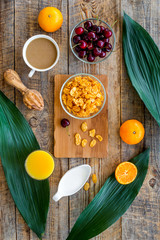 Light summer breakfast. Muesli, oranges, cherry, croissant and coffee on wooden table background top view