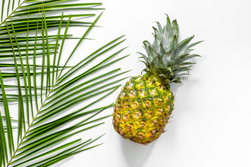 Fototapeta premium Pineapple and palm branch on white background top view copyspace
