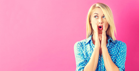 Surprised young woman posing on a pink background