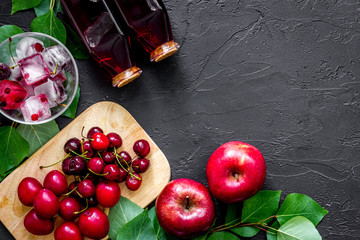 Summer ice fruit drink with apple, pulm and cranberry on black table top view copyspace