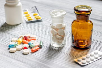 Vitamins and supplements. Pills and pill bottle on grey wooden table background