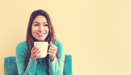 Young latina woman drinking coffee while sitting