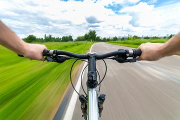 Photo sur Plexiglas Vélo Rider driving bicycle on an asphalt road. Two hand on bike handlebar. Motion blurred background
