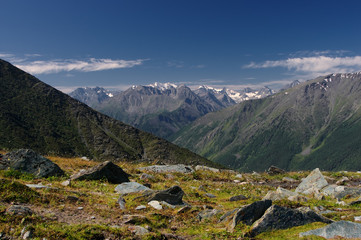 Fototapeta na wymiar Mountain valley on the background of ranges and snow peaks view from above top height with rocks and alpine meadow in the foreground Altai Mountains Siberia, Russia