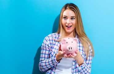 Fototapeta na wymiar Happy woman holding a piggy bank on a blue background