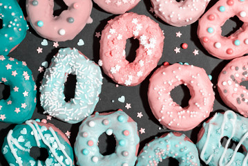 Colorful glazed donuts on a chalky black background