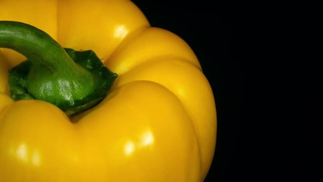 Amazing top of yellow sweet pepper close up, rotating clockwise with side center on black background. Vibrant natural texture of fresh vegetable in 4k, 3840x2160, clip. Eco product for healthy food.
