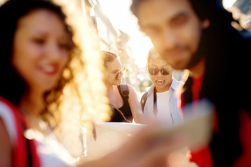 Group of tourists searching for places on their map outdoors.