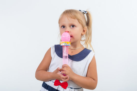 A little girl is singing a cheerful song into the microphone. Happy carefree childhood.