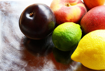 Fresh ripe organic fruits on vintage metal plate background.Lemon,lime,plum,mango and peaches.Diet,healthy food,raw food concept.Selective focus.