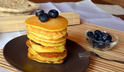 Stack of sweet homemade pancakes with fresh blueberries on a plate.