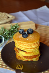 Stack of sweet homemade pancakes with fresh blueberries on a plate.