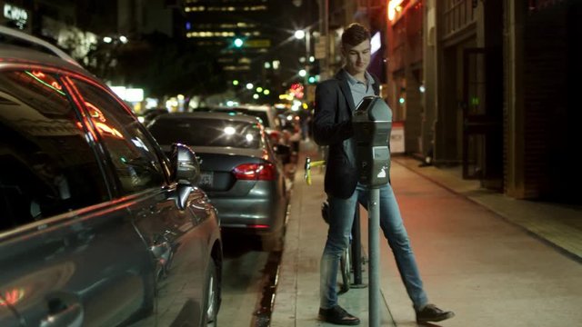 Young man is paying for a parkking lot on a street