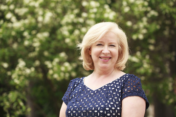 Fototapeta premium Happy elderly woman on the background of summer park