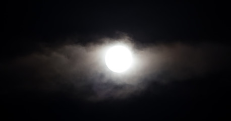 The moon in the haze of the clouds at night