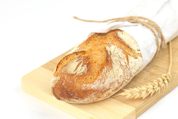Fresh French baguette in paper wrap on wood board with white background