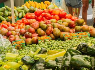 Farmer's market produce for sale at stand. Color horizontal photo of heirloom tomatoes, cherry tomatoes, brussel sprouts, zucchini, squashes, gypsy peppers and bell peppers are visible.
