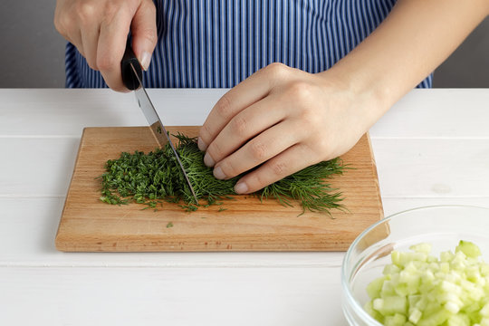 Step by step recipe for tarator. Hands cut a dill on board in the kitchen.