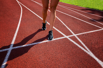 Fototapeta na wymiar Red running track with female runner, close up on shoes