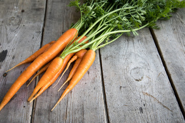 fresh carrots bunch on wood. Bunch of fresh carrots with green leaves. Raw food ingredients
