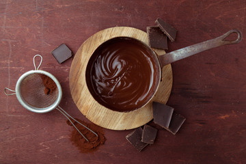 Melted chocolate swirl in pan on the wooden background