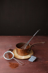 Melted chocolate in pan with whisk on the wooden background