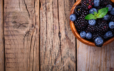 Fototapeta na wymiar Blackberry and Blueberry with Mint. Fresh Berry in a wooden bowl on a wooden Vintage Background.Food or Healthy diet concept.Vegetarian.Copy space for Text.selective focus