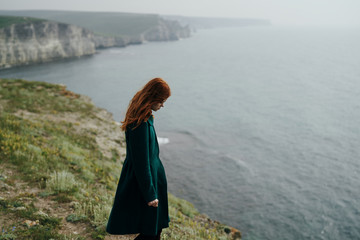 Young beautiful woman on a cliff of a mountain near the sea