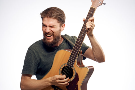 Young guy with a beard on a white isolated background holds a guitar