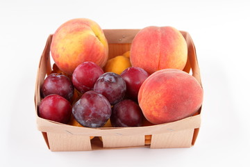 Peaches, apricots and plums in a basket isolated on white background