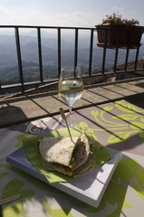 A glass of wine and pita on the terrace. Blurred mountains on the background