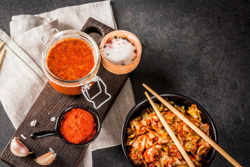 Asian cuisine. Fermented food. Traditional Korean dish: kimchi cabbage - sauerkraut with traditional kimchi sauce from hot red chili pepper, garlic, spices, salt. On a black stone table. Copy space