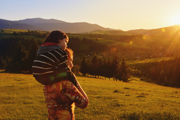 Mom and baby stand and watch the sunset in the mountains