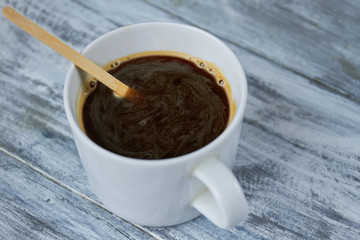Dark coffee and stir stick. Espresso on wooden table.