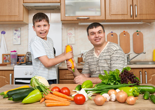 Father and son having fun with vegetables in home kitchen interior. Man and child. Fruits and vegetables. Healthy food concept