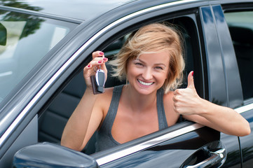 Young happy woman showing the key of new car.