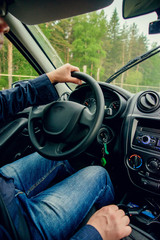 Young man or student behind the wheel. He is looking at camera and smiling.