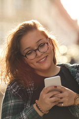 Smiling beautiful woman using cellphone outdoors.