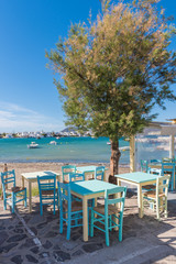 Colorful tables and chairs on coastal promenade in Pollonia village on Milos Island. Greece.