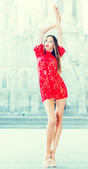 portrait of sexy young woman in red dress walking in the old city