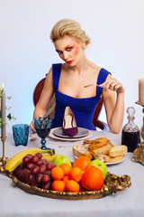 Crazy about footwear girl eating velvet shoe behind the table served for festive dinner